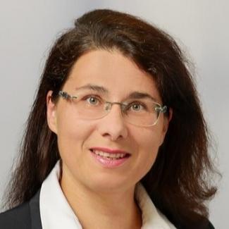 Das Portrait einer Frau mit baunen Haaren und randloser Brille